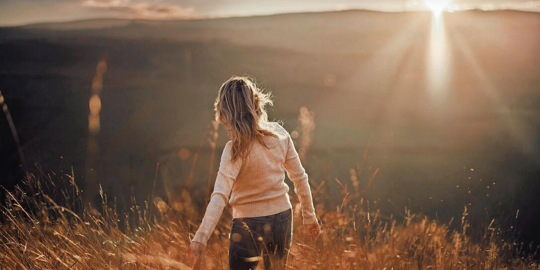 Back view of carefree woman in autumn day on a hill at sunset.