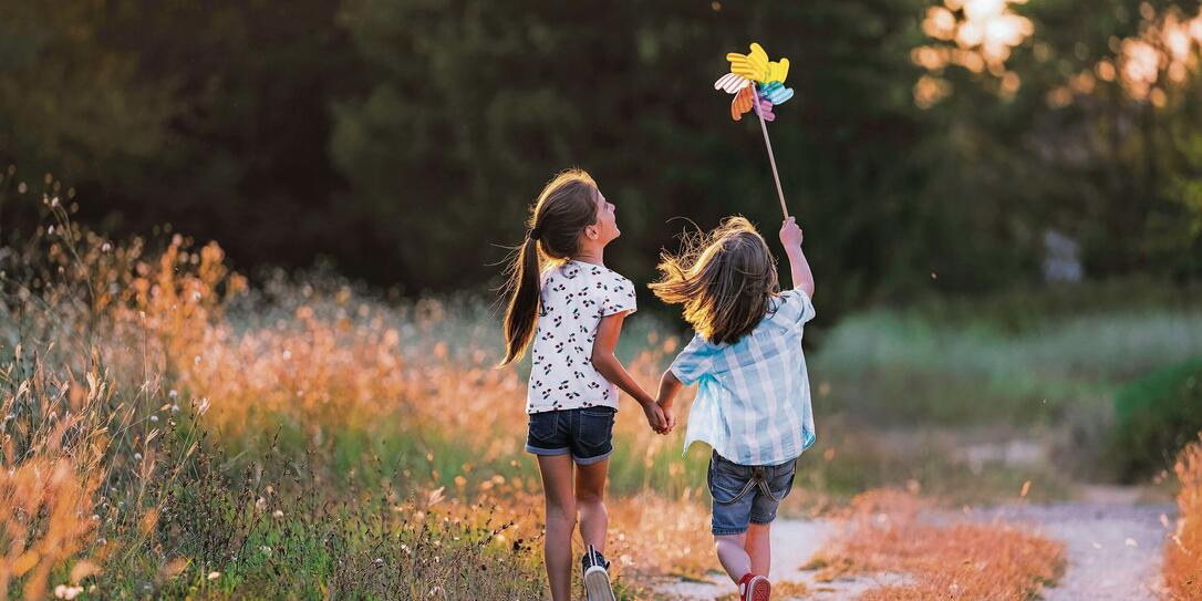 Happy Kids having fun with pinwheel in the nature. Running kids