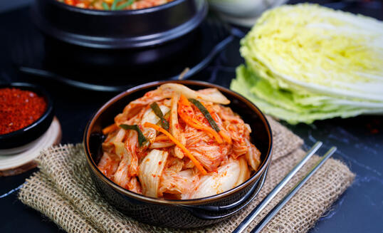 Eating kimchi cabbage and rice in a black bowl with chopsticks, Korean food.