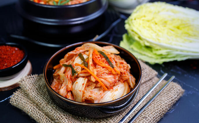 Eating kimchi cabbage and rice in a black bowl with chopsticks, Korean food.